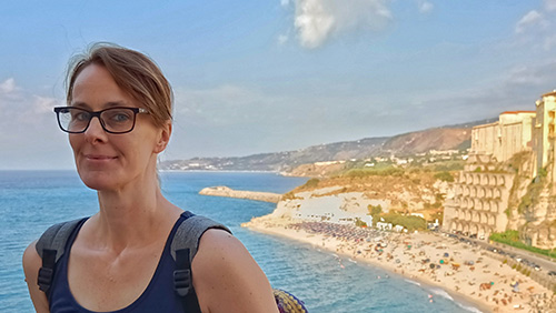 Porträtbild einer Frau; im Hintergrund Tropea und die Küste von Kalabrien.